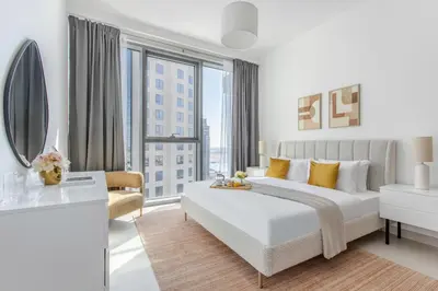 a white bedroom with a bed and a large window at Frank Porter - The Grand in Dubai