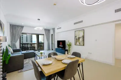 a dining room and living room with a table and chairs at 1BR in Palm Jumeirah, Walk to the Beach and Mall in Dubai