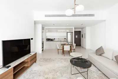 a living room with a couch and a tv and a table at Silkhaus Marina View with Tower's Private Beach in Dubai