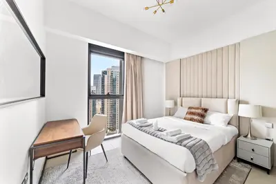 a white bedroom with a bed and a desk and a window at Luxury 2 Bedroom Apartment - Next to Dubai Opera in Dubai