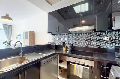 a kitchen with black cabinets and a stainless steel sink at Botanica Tower - Bright One Bedroom in Dubai