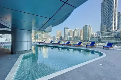 a swimming pool with blue chairs and a city skyline at The Point Tower - Chic One Bedroom in Dubai