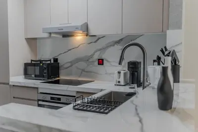 a white kitchen with a sink and a counter top at Clever Guest Concorde JLT in Dubai