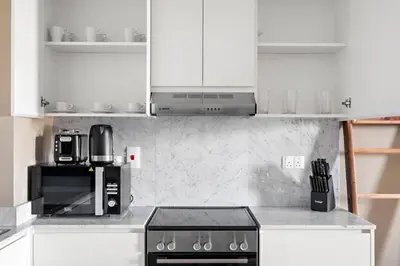a kitchen with white cabinets and a black microwave at StoneTree - Cozy 1 BR near Madinat Jumeirah and Burj Al Arab in Dubai