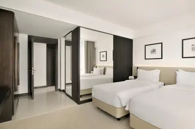 a hotel room with two beds and a mirror at Sheraton Grand Hotel, Dubai in Dubai