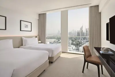 a hotel room with two beds and a desk and a window at Sheraton Grand Hotel, Dubai in Dubai