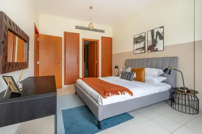 a bedroom with a bed with a desk and a television at GuestReady Holiday Homes - One Mint Sunset in Dubai