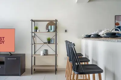 a kitchen with two black chairs and a counter at GuestReady Holiday Homes - One Mint Sunset in Dubai
