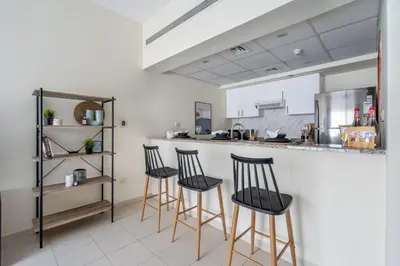 a kitchen with four bar stools in front of a counter at GuestReady Holiday Homes - One Mint Sunset in Dubai