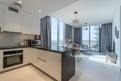 a kitchen with white cabinets and a dining room with a view at Residence 12 I District One I 1 Bedroom Apartment in Dubai