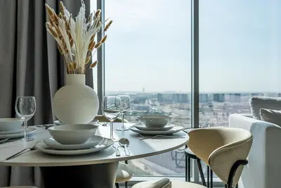 a table with glasses and a vase on it with a window at Residence 12 I District One I 1 Bedroom Apartment in Dubai