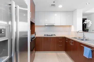 a kitchen with wooden cabinets and a stainless steel refrigerator at Vacay Lettings - Burj Vista Tower 1- Direct Dubai Mall Access in Dubai