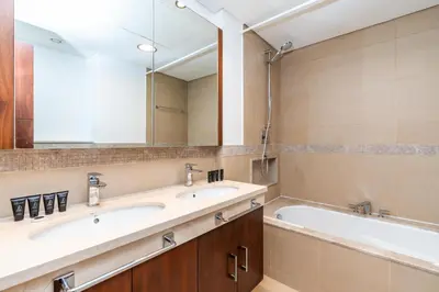 a bathroom with two sinks and a tub and a mirror at Vacay Lettings - Burj Vista Tower 1- Direct Dubai Mall Access in Dubai