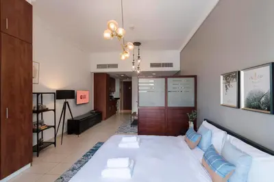 a living room with a large white bed with blue pillows at GuestReady Holiday Homes - Hibernate Hideout in Dubai