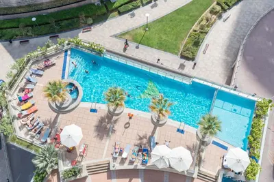 an overhead view of a swimming pool with palm trees and umbrellas at GuestReady Holiday Homes - Hibernate Hideout in Dubai