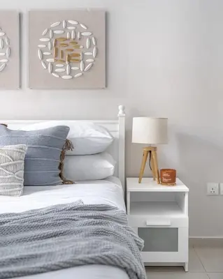 a white bedroom with a bed and a lamp at GuestReady - Comfort Stay l Close To Marina Mall in Dubai