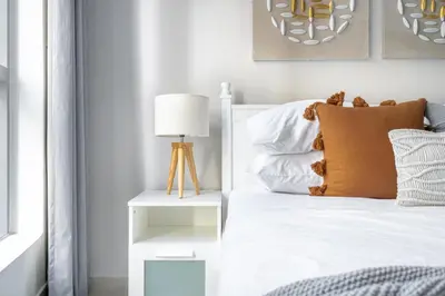 a bedroom with a white bed with a brown pillow at GuestReady - Comfort Stay l Close To Marina Mall in Dubai