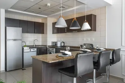 a kitchen with a large island with black chairs at GuestReady - Comfort Stay l Close To Marina Mall in Dubai