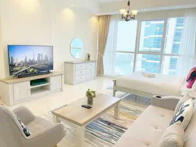 a white living room with a bed and a tv at RH- Beautiful Canal View, Cozy studio near metro station in Dubai