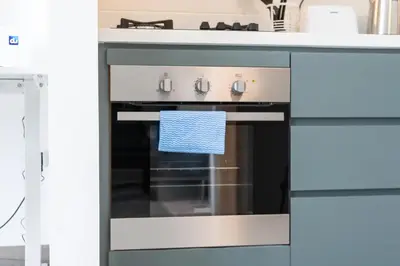 a kitchen with an oven with a blue towel on it at Luxury & Stylish Studio - JVC in Dubai