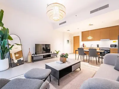 a living room with couches and a table and a kitchen at Coastal Charm Casita : 1BR Creek Beach Elegance in Dubai