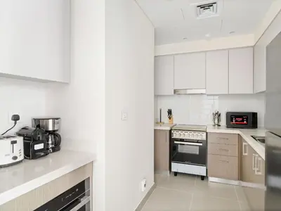 a kitchen with white cabinets and a stove top oven at Sophisticated and Trendy 2BDR In Forte Downtown in Dubai