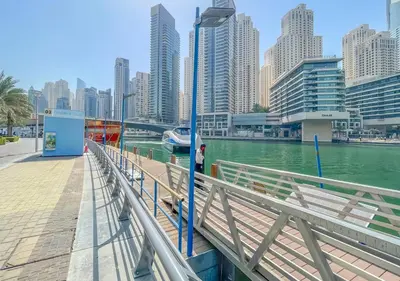 a person standing on a pier next to a river with buildings at Luxury 1BR Apartment in the heart Marina, Connection to Dubai Marina Mall - Silverene tower in Dubai