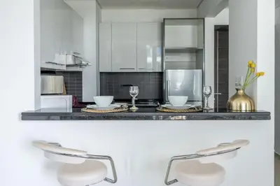 a kitchen with a counter with two bar stools at GuestReady - Marina View Studio l With Balcony in Dubai