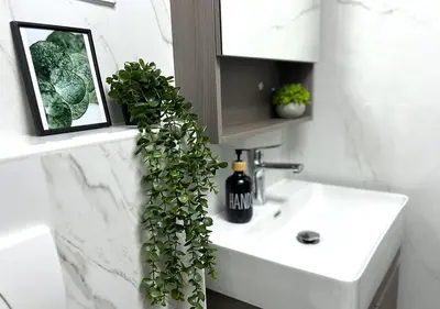 a bathroom with a white sink and a green plant at Lake View 1BR Apt Balcony & Near DMCC Metro in Dubai
