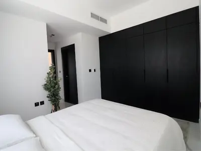 a bedroom with a large white bed and a black cabinet at VESTA - Dubai Residence in Dubai