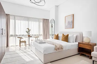 a white bedroom with a large bed and a table at Silkhaus Bright Studio Near Silicon Central Mall in Dubai