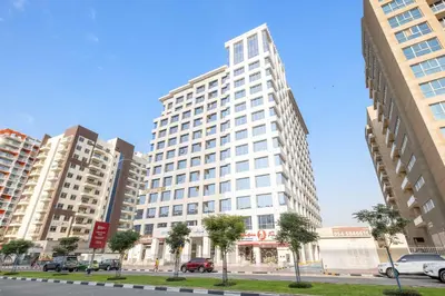 a tall white building with cars parked in a city at Silkhaus Bright Studio Near Silicon Central Mall in Dubai