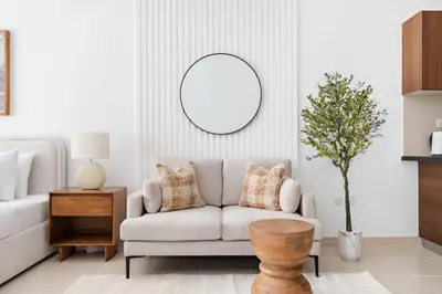 a living room with a couch and a mirror at Silkhaus Bright Studio Near Silicon Central Mall in Dubai