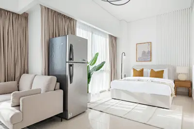 a white bedroom with a refrigerator and a bed at Silkhaus Luxury Studio in Residential Neighborhood in Dubai