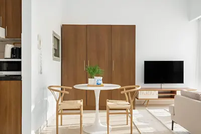 a living room with a table and chairs and a tv at Silkhaus Luxury Studio in Residential Neighborhood in Dubai