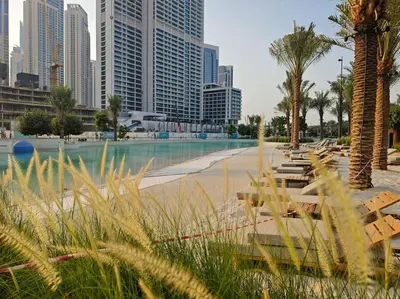a park with benches and palm trees in a city at Zen Oasis : 1BR Splendid Creek Side Retreat - Beach in Dubai