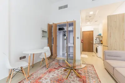 a living room with a couch and a table and chairs at HAVN - Studio Apartment in Pantheon Elysee, JVC in Dubai