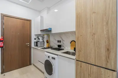 a kitchen with a washing machine and a door at HAVN - Studio Apartment in Pantheon Elysee, JVC in Dubai