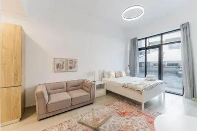 a white bedroom with a bed and a couch at HAVN - Studio Apartment in Pantheon Elysee, JVC in Dubai