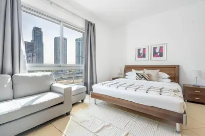 a bedroom with a bed and a couch and a window at GuestReady - Bright 1BR with Balcony & Marina View in Dubai