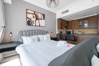 a bedroom with a large bed and a kitchen at HAVN - Studio Unit in 8 Boulevard, Downtown Dubai in Dubai