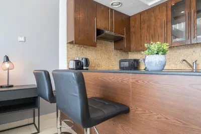 a kitchen with a bar with two chairs and a sink at HAVN - Studio Unit in 8 Boulevard, Downtown Dubai in Dubai