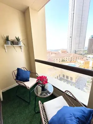 a room with a balcony with chairs and a table at Seaside Spacious Studio with Vibrant Vibes in JBR By SWEET HOMES in Dubai