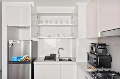 a kitchen with white cabinets and a stainless steel refrigerator at Silkhaus High Floor 1BDR with View with Pool & Gym in Dubai