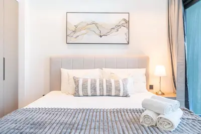 a bedroom with a white bed with a blue blanket at HAVN - Studio Unit in 15 Northside, Business Bay in Dubai