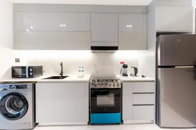 a white kitchen with a stove and a dishwasher at HAVN - Studio in Business Bay, Burj Khalifa View in Dubai