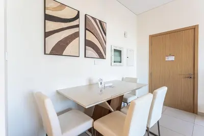 a dining room with a table and white chairs at HAVN - 2 Bedroom in Bayshore, Dubai Creek Harbour in Dubai
