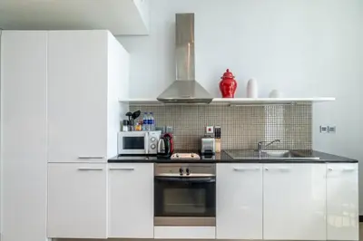 a white kitchen with white cabinets and a microwave at GuestReady- Holiday Homes - Cyan Sky View in Dubai
