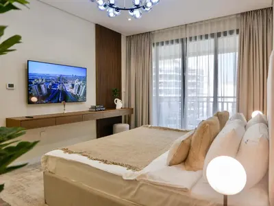 a bedroom with a large bed and a flat screen tv at Ambient 1BR Apartment On The Beach at 5 Star Resort in Dubai