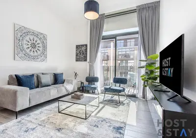 a living room with a couch and a tv at Unique 1BR in Belgravia Square, JVC - Host & Stay in Dubai
